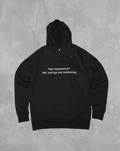 Black heavyweight hoodie with front text 'High maintenance? Nah, just high and maintaining' – 400 GSM thick premium streetwear hoodie for men and women.