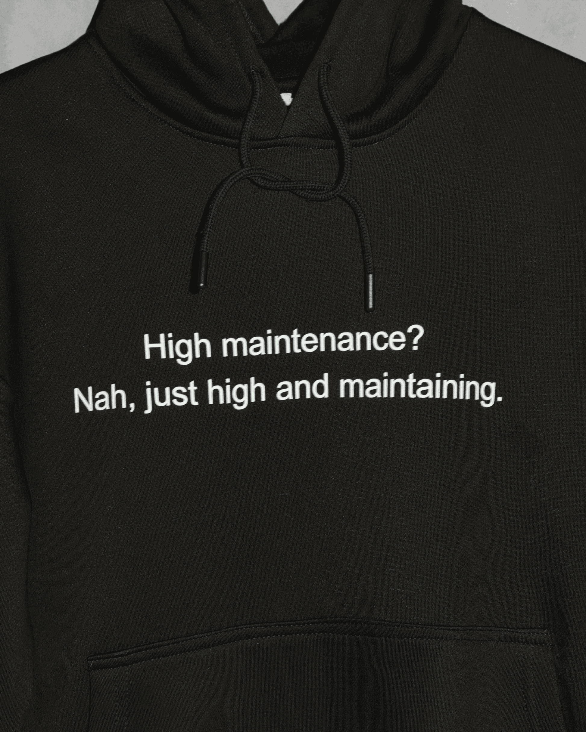 Black heavyweight hoodie with front text 'High maintenance? Nah, just high and maintaining' – 400 GSM thick premium streetwear hoodie for men and women - zoomed in.