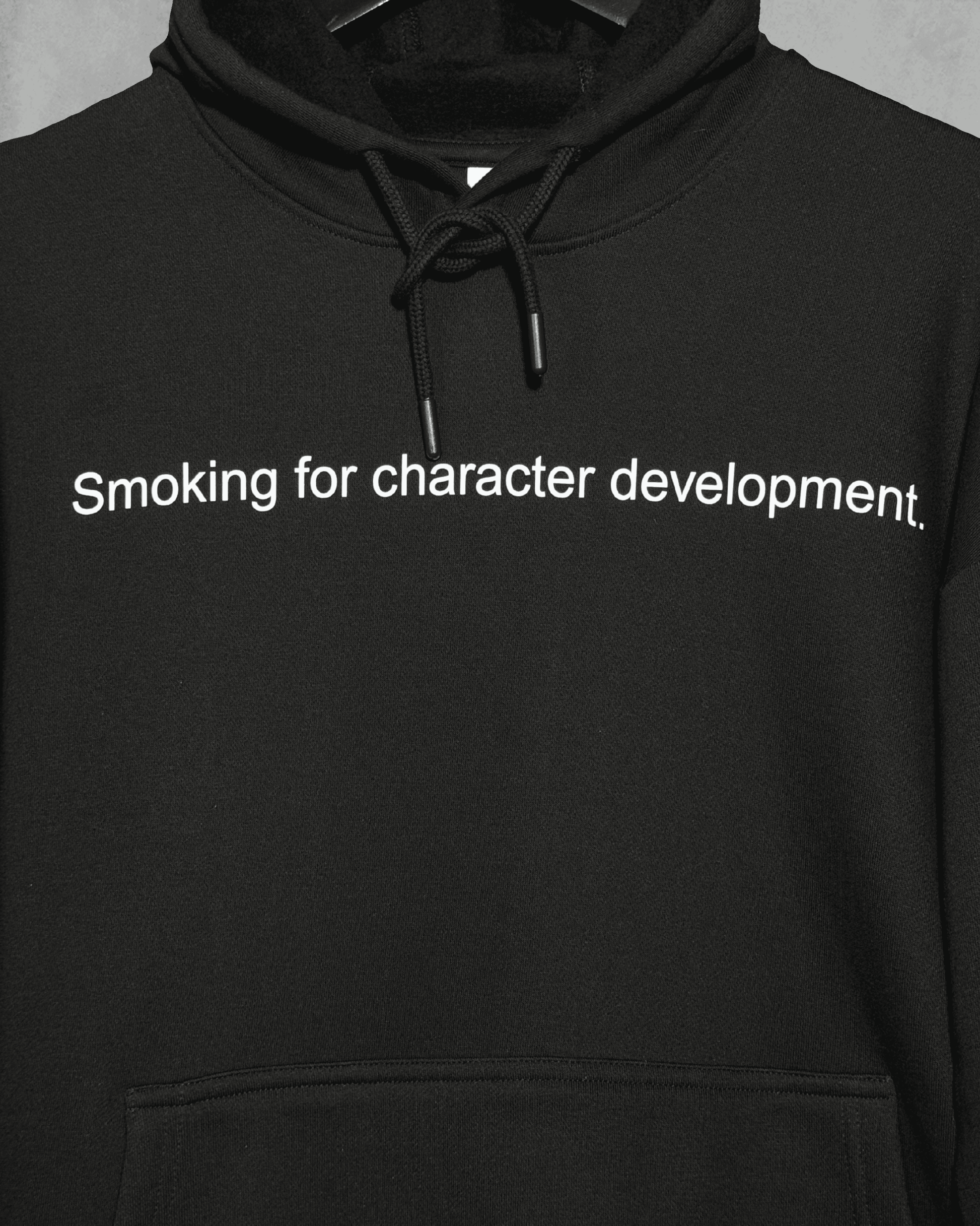 Black heavyweight hoodie with front text 'Smoking for character development' – 400 GSM thick premium streetwear hoodie for men and women - zoomed in.