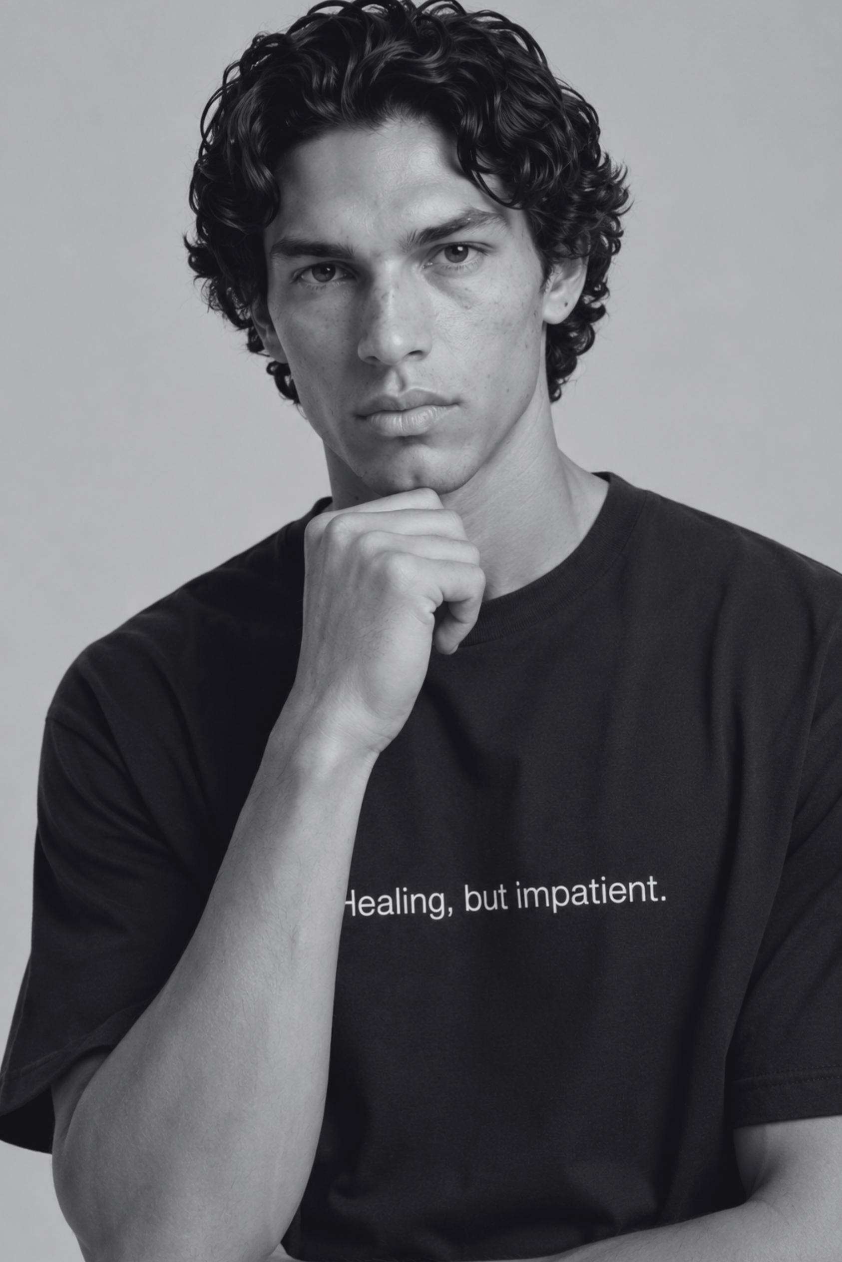 A close up shot of a person wearing a black t-shirt with text 'Healing, but impatient' with 240 GSM premium streetwear t-shirt for men and women.