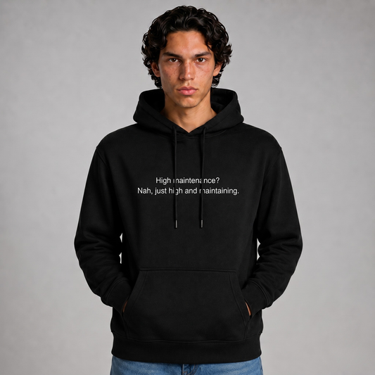 Person wearing a black thick hoodie with text 'High maintenance? Nah, just high and maintaining'  with 400 GSM premium streetwear hoodie for men and women and blue jeans on a gray background.