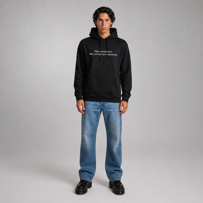 Person wearing a black thick hoodie with text 'High maintenance? Nah, just high and maintaining'  with 400 GSM premium streetwear hoodie for men and women and blue jeans on a gray background