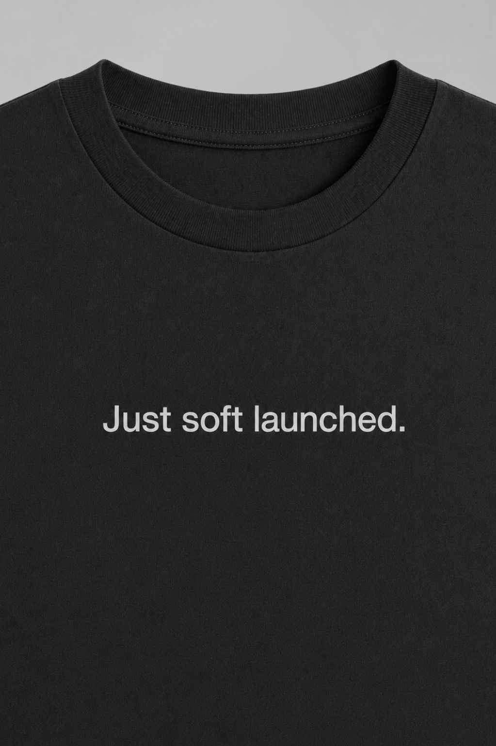 Black t-shirt with 'Just soft launched.' text on a gray background