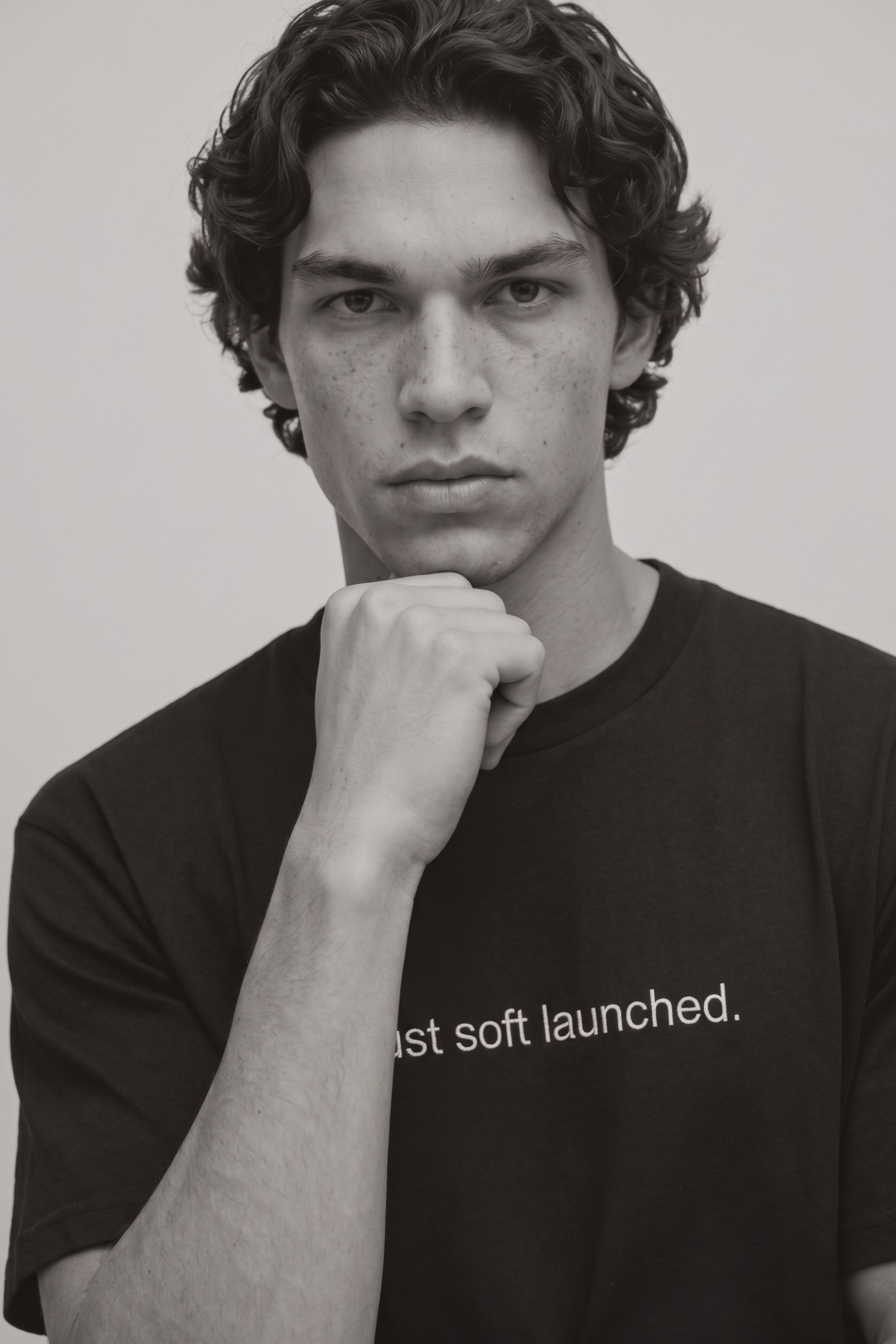 A close up shot of a person wearing a black t-shirt with text 'Just soft launched' with 240 GSM premium streetwear t-shirt for men and women.
